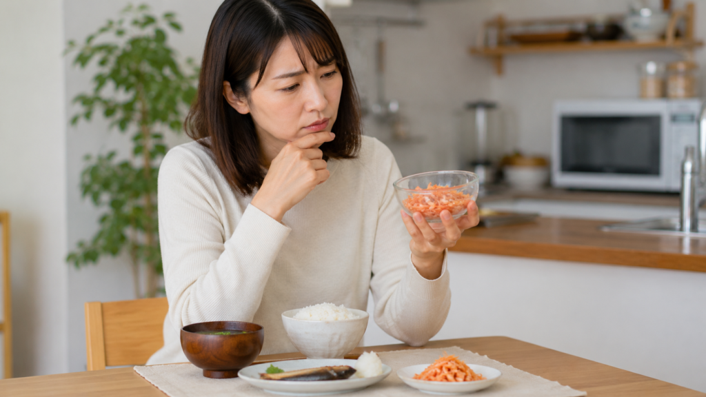 干しエビの適量やプリン体を気にしながら小鉢を見つめる日本人女性