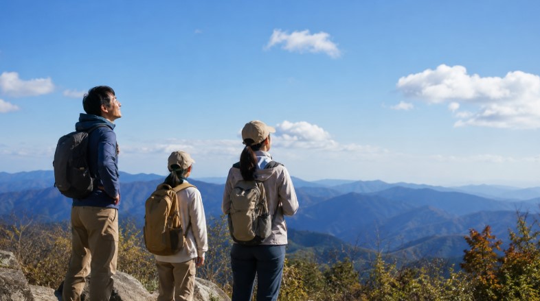 高尾山の山頂で達成感を味わいながら山並みを眺める家族ハイカー