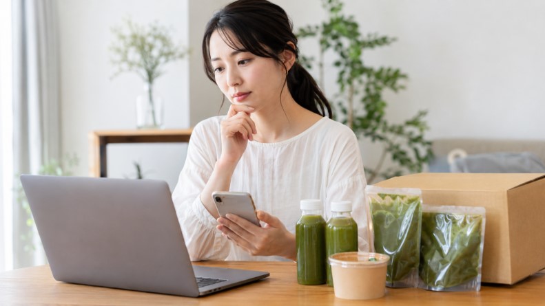 グリーンブラザーズ解約前にスマホとパソコンで定期購入や初回特典を確認する女性