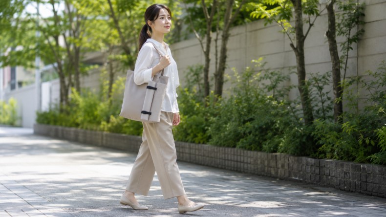 日傘をバッグの外側に固定して持ち歩く日本人女性